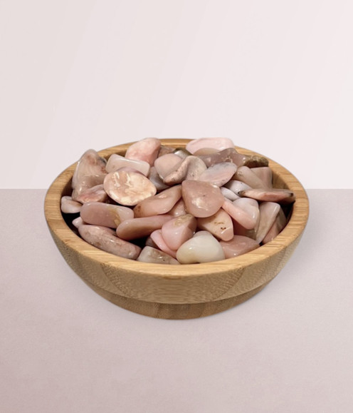Pink Opal - a bowl of assorted tumbled pieces, against a light pink background.
