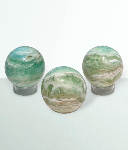Caribbean Calcite Orbs - a variety of pieces in a small size, against a cool blue-green coloured background.