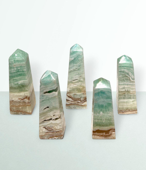 Caribbean Calcite Points - a variety of pieces in various sizes, against a cool blue-green coloured background.