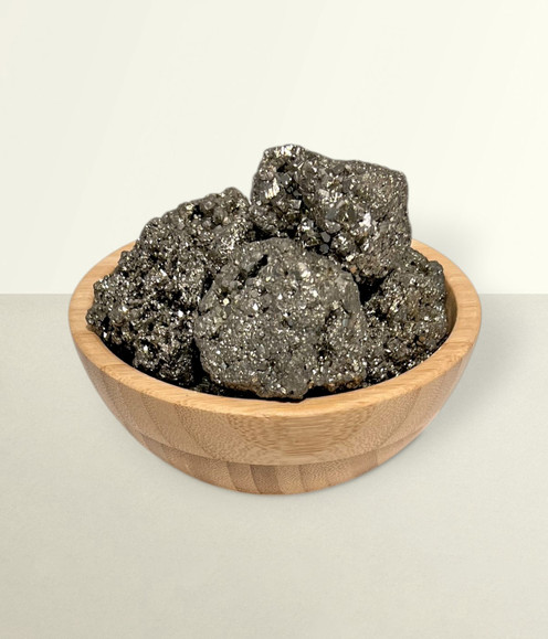 Pyrite Raw - a bowl of assorted raw chunks & pieces, against a light cream coloured background.
