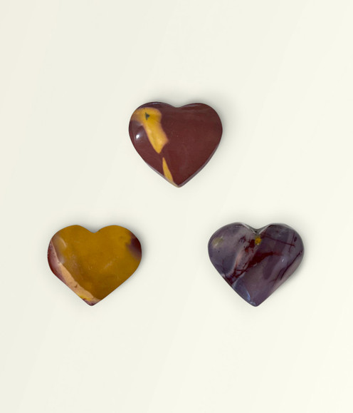 Mookaite - a variety of heart-shaped pieces in small sizes, against a warm yellow background. Mookaite - a variety of heart-shaped pieces in small sizes, against a warm yellow background.