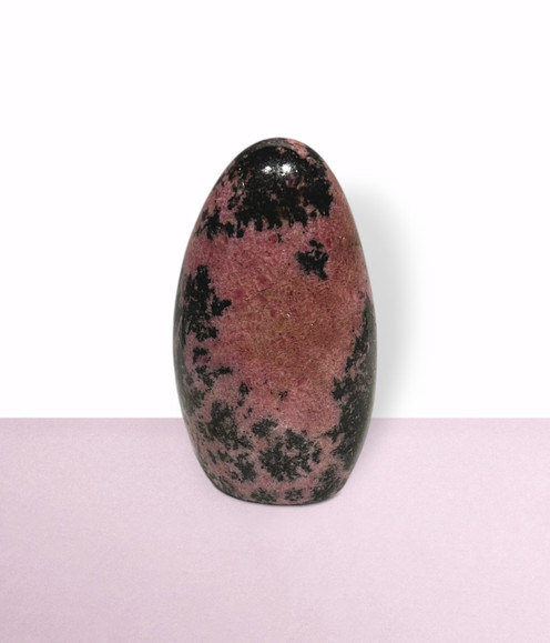 Rhodonite Free Form - solo piece #2, from the front, against a light pink coloured background. Rhodonite Free Form - solo piece #2, from the front, against a light pink coloured background.