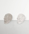 Clear Quartz Skull Carvings, two samples angled to the right side, front-facing, against a pale grey coloured background.