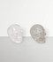 Clear Quartz Skull Carvings, two samples angled to the left side, front-facing, against a pale grey coloured background.