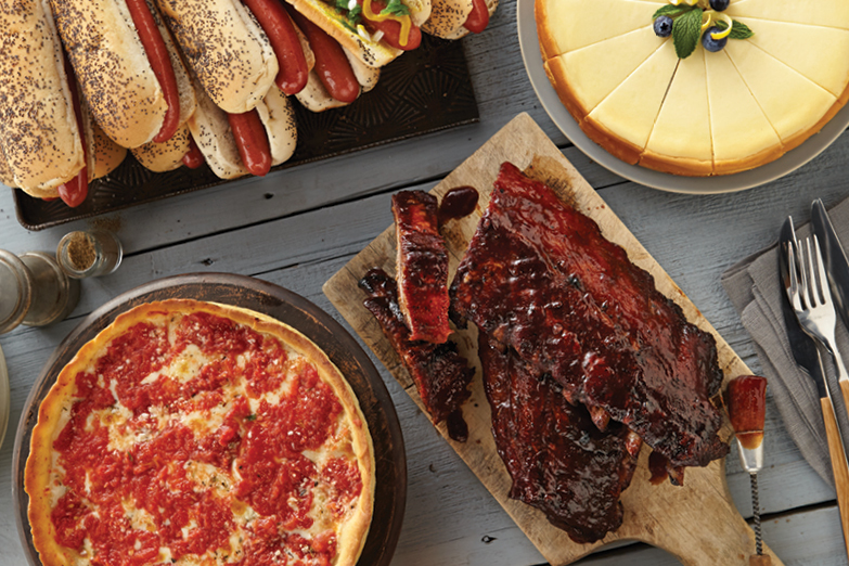 ribs, hot dogs, pizza, and cheesecake on a table