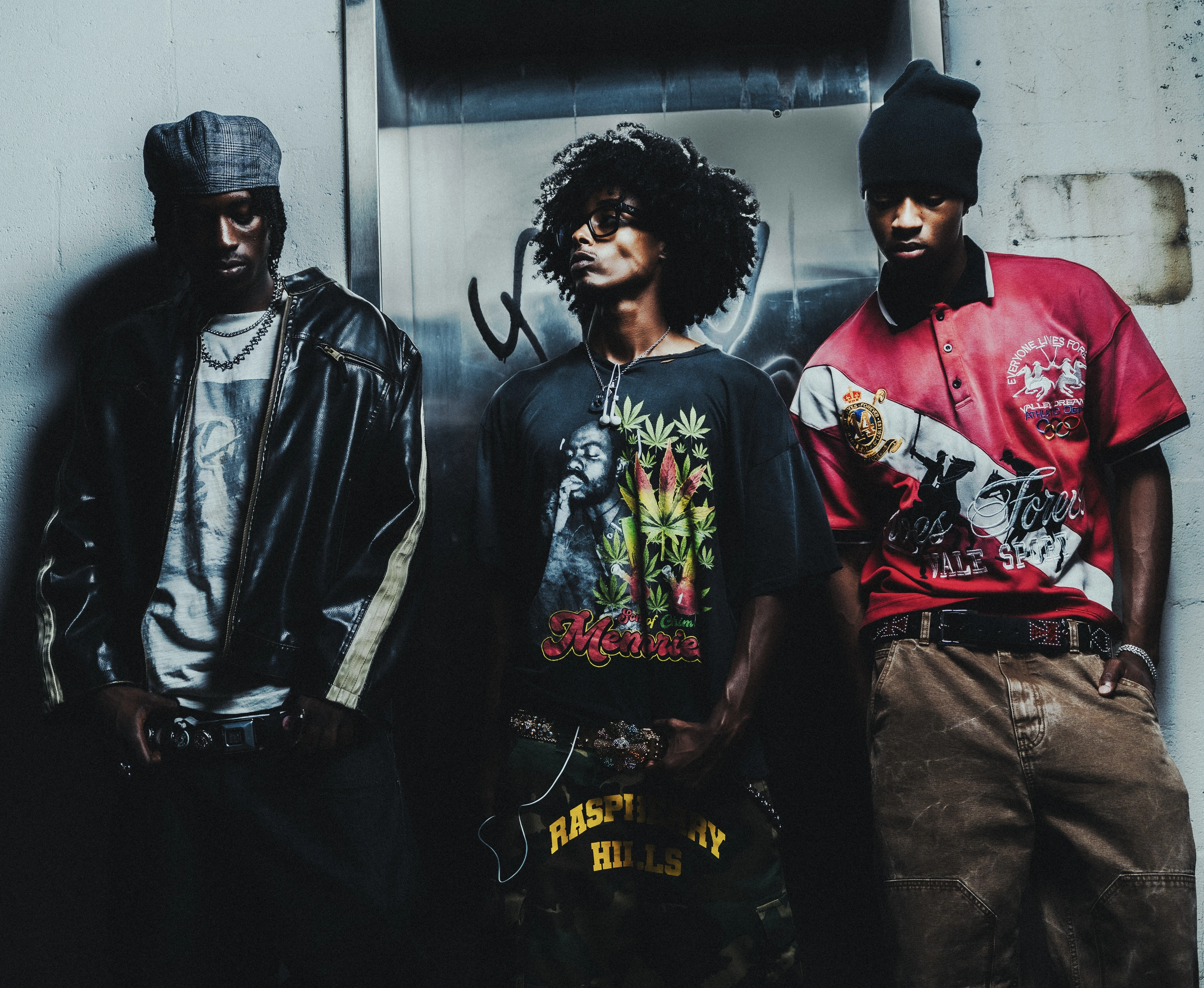 Three models wearing layered streetwear and graphic tees