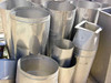 Outdoor grouping of full stainless steel ventilation duct lot showing round cylinders, square adapters, and transition pieces