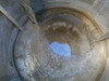 Interior view looking down into stainless steel 350 gallon tank showing bottom outlet port and residue on tank walls