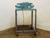 AIE AIE-605A1 impulse heat sealer on rolling steel cart, rear three-quarter view showing power cord and foot pedal