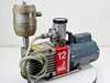 Edwards E2M12 vacuum pump – left-side three-quarter view showing GE motor, oil mist filter, foreline trap, and braided hose