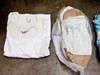 Folded white Gore-Tex cleanroom top with label tag alongside bagged cleanroom garments including boot forms on cardboard inserts