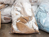 Large plastic bag containing white Gore-Tex cleanroom garments and tan boot forms on cardboard