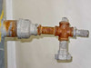 Close-up of right-side 1-inch pipe fitting with heavily rusted cross-pattern valve body and threaded connections