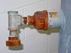 Close-up of left-side 1-inch pipe fitting showing rusted globe valve and threaded union connector