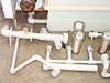 PVC pipe manifold assembly with inline filter housings and ball valves showing signs of rust on center pipe section — side view
