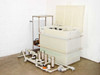 HDPE chemical reservoir tank with lid open showing interior piping connections and control panel — full system three-quarter view with filter manifold