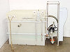 Full system side view showing HDPE tank with dual Helicoid pressure gauges, PVC plumbing on tank exterior, pump cabinet, and stainless steel rack frame