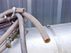 Bundle of braided flex hoses and brass ball valve fittings — one hose end showing internal rust and corrosion, hose clamps and connectors visible