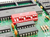 JCC 800310 close-up of 10-position Grayhill red DIP switch and HM8250B 9027AB controller chip on PCB