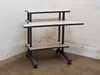3-tier mobile computer desk — left-front angle view showing all three white laminate shelves and dark steel frame on casters