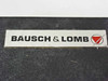 Bausch & Lomb label on black granite base — white and red logo plate reading 'BAUSCH & LOMB' with red chevron logo