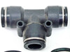 Close-up of large black SMC T-style push-to-connect fitting showing three-port configuration and stainless collet rings