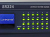 Linksys SR224 front panel close-up showing Linksys logo, port LEDs 1–24 all lit green, and System indicator