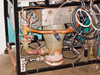 Under-cart rear view showing copper vacuum tubing, large bellows-flex hose connection to diffusion pump, and gas/water plumbing