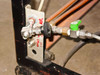 Close-up of frame-mounted gas/water valve manifold — hand-labeled 'Air' and 'Water In' with compression fittings and ball valves