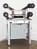 Industrial laminating press station full front view showing stainless steel platen, film roll arbors, and control panel with green and red pushbuttons