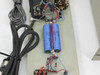 Close-up of internal board showing two blue 6300uF 100VDC cylindrical electrolytic capacitors, relay block, and multi-conductor wiring harness — detail view