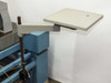 Side-mounted articulating arm with flat white work shelf attached to blue isolation table frame