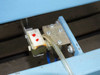 Close-up of pneumatic solenoid valve with red indicator dots and clear tubing attached to blue frame
