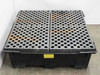 Spill containment sump pallet viewed from the front corner showing grating panels separated at center seam and sump basin walls