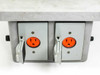 Front of enclosure showing two switched 110V AC outlets with orange indicator faces and flip covers