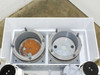 Top-down view into HDPE mixing tank showing two circular process bath openings with stainless flanges and residue
