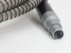 Lumatec fiber optic light guide close-up of output-end cylindrical barrel connector showing fiber bundle aperture and knurled metal ferrule, stainless armored cable visible