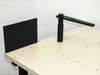 Corner detail of table surface showing vertical black post with horizontal arm and black side panel mounted at tabletop edge