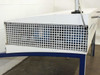 End-panel view of laminar flow hood showing square-grid intake/exhaust grille on the short face of the white enclosure, blue stand leg visible