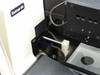 Sloan Dektak IIA scan head — close-up of stylus arm and stage mechanism showing stylus needle, spring, and sample positioning hardware; 'Dektak IIA' label visible
