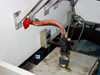 Internal water supply area showing red-handled shutoff valve, flexible hose, and drain components