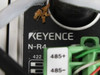 Close-up of Keyence N-R4 communication amplifier label showing model number, RS-422 and RS-485 terminal connections with debris visible on surface