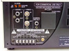Panasonic AG-RT600P rear panel close-up showing V-LOCK selector, 2h/8h/24h/40h SP/SLP mode switch, RCA audio and video connectors, Camera SW Out, alarm terminal block with Alarm In, Tape End Out, Warning Out, and GND