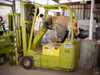 Clark TW30B 3-wheel electric forklift — left side view showing yellow painted body, mast, and forks in warehouse setting