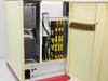 Opcom D.I.A.L. PBX system interior – open cabinet door showing multiple card slots with yellow and green plug-in modules, ribbon cables, and power supply section