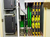Opcom D.I.A.L. PBX interior close-up – card cage with numbered slots 2 through 8, yellow and green plug-in line cards, and dual Micropolis 1335 MFM hard drives on left