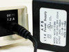 Cayman 3220-H DSL Router power input close-up showing 9V 1.2A DC barrel jack on unit and APS ITE power supply label: INPUT 120V 60Hz 25W, OUTPUT 9VDC 1500mA, Model D9-15-950
