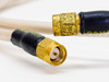 Close-up of both SMA male connector ends showing gold-plated threads and center pin detail with black strain relief boots