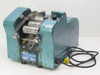 Burnett Bros Engineering industrial label applicator front-left view showing blue cast housing, roller mechanism, and power cord with plug