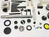 Detail view of microscope parts including chrome post, black dust caps, focus knobs, gear ring, yellow filter, small hardware, and flat plate assemblies